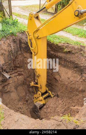 Hydraulikbaggerkolben gräbt tiefe Grube im Industriegebiet auf der Baustelle. Stockfoto