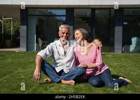 Älterer Mann und alternde Dame sitzen vor dem Haus zusammen Stockfoto