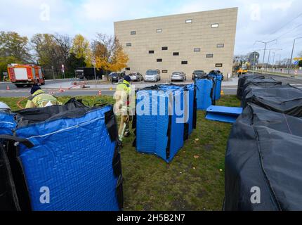 Dresden, Deutschland. November 2021. Feuerwehrleute sind damit beschäftigt, vor der Synagoge mobile Straßensperren mit Wasser zu machen. Am 9. November 2021 findet das Gedenken an die Opfer der Pogromnacht vom 9. November 1938 statt und die jüdische Gemeinde feiert 20 Jahre Weihe der Neuen Synagoge Dresden. Quelle: Robert Michael/dpa-Zentralbild/dpa/Alamy Live News Stockfoto