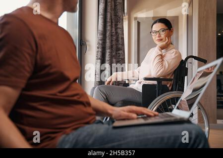 Mann, der online arbeitet und mit einer behinderten Frau kommuniziert Stockfoto