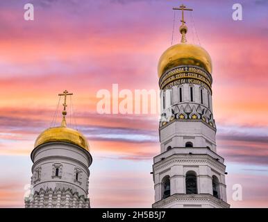 Goldene Zwiebelkuppen von Ivan dem Großen Glockenturm & Dormition oder Mariä-Himmelfahrt-Kathedrale mit farbenprächtigem Himmel bei Sonnenuntergang, Kreml, Moskau, Russland Stockfoto