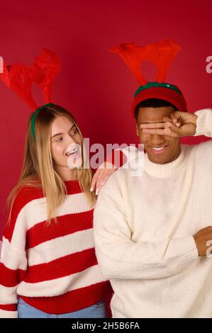 Zwei junge Menschen in gehörnten Hüten auf rotem Hintergrund Stockfoto