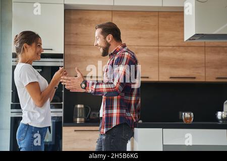 Glücklicher, schöner Mann, der sich aufgeregt fühlt, während die Frau den Schwangerschaftstest in den Händen hält Stockfoto