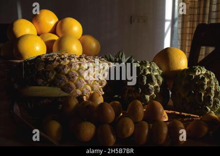 Verschiedene Früchte wie Ananas, malta, Orangen, Puddingäpfel, frische gelbe knusprige Datteln auf dem Esstisch für das Frühstück am Morgen. Esstisch im Innenbereich Stockfoto