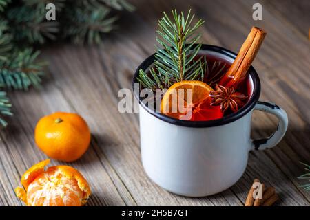 Traditioneller leckerer Glühwein mit Mandarinapfelgewürzen und weihnachtsbaum in weißer Tasse. Heißes Getränk im Herbst Stockfoto