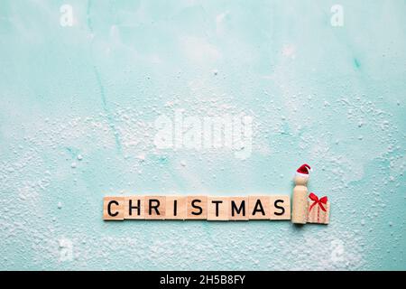 Weihnachtsmann mit dem Text Weihnachten und Geschenkbox mit roter Schleife auf blauem Hintergrund mit Schnee, Frohe Weihnachten, Urlaub, Geschenk-Konzept mit Kopierraum Stockfoto