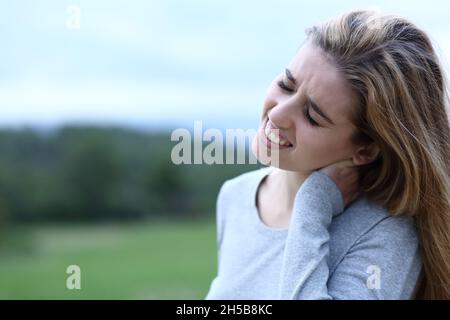 Teenager Mädchen leiden Nackenschmerzen im Freien auf einem Feld Stockfoto