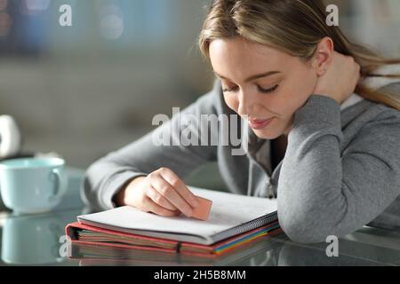 Schüler löschen Text auf Notizbuch mit Radierer zu Hause Stockfoto