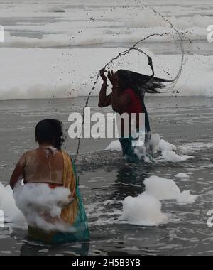 Neu-Delhi, Indien. November 2021. Giftiger Schaum schwimmt auf der Oberfläche des verschmutzten Yamuna-Flusses, während hinduistische Anhänger am Montag, den 8. November 2021, im Rahmen der Rituale des viertägigen „Chhath Puja“-Festivals in Neu Delhi, Indien, ein Bad nehmen. Das alte hinduistische Fest, das dem sonnengott gewidmet ist, wird für das Wohlergehen, die Entwicklung und den Wohlstand der Familienmitglieder gefeiert. Foto von Abhishek/UPI. Kredit: UPI/Alamy Live Nachrichten Stockfoto