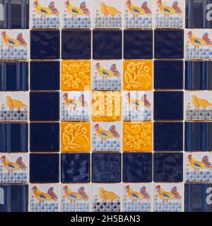 Fragment der Gebäudewand mit bunten keramischen Wandfliesen. Azulejos aus nächster Nähe. Abstrakt dekorativer Hintergrund. Traditionelle, reich verzierte portugiesische Kunst Stockfoto