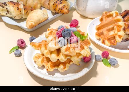 Modernes Dessert-Croffle: Eine Mischung aus Croissants und Waffeln, Waffeleisen-Pfanne mit Waffeleisen, Beerenfrüchten und Schokolade Stockfoto