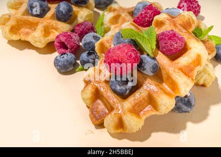 Modernes Dessert-Croffle: Eine Mischung aus Croissants und Waffeln, Waffeleisen-Pfanne mit Waffeleisen, Beerenfrüchten und Schokolade Stockfoto