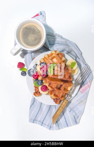 Modernes Dessert-Croffle: Eine Mischung aus Croissants und Waffeln, Waffeleisen-Pfanne mit Waffeleisen, Beerenfrüchten und Schokolade Stockfoto