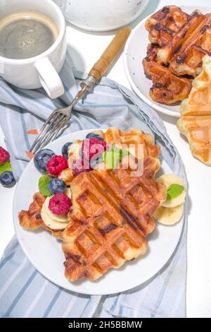 Modernes Dessert-Croffle: Eine Mischung aus Croissants und Waffeln, Waffeleisen-Pfanne mit Waffeleisen, Beerenfrüchten und Schokolade Stockfoto