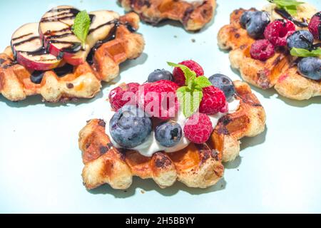 Modernes Dessert-Croffle: Eine Mischung aus Croissants und Waffeln, Waffeleisen-Pfanne mit Waffeleisen, Beerenfrüchten und Schokolade Stockfoto