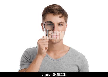 Lächelnd lustig junge kaukasische gut aussehende männlich Blick durch Vergrößerungsglas Stockfoto