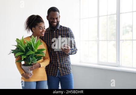 Frohes junges schwarzes Männchen und Weibchen, das in neuem Haus und in der Planung des Innenraums umzieht, wählen Sie Hausentfernungsservice Stockfoto