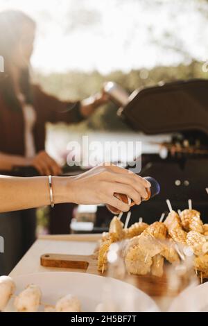 Weibliche Freunde, die während der Abendparty am sonnigen Tag Essen zubereiten Stockfoto