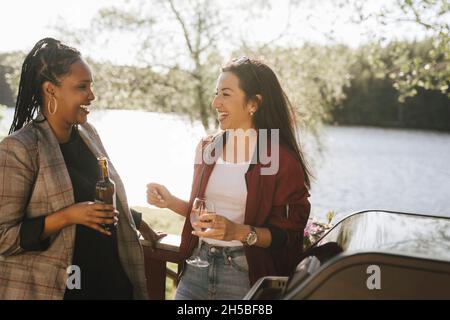 Glückliche multirassische Frauen, die am sonnigen Tag beim Trinken reden Stockfoto