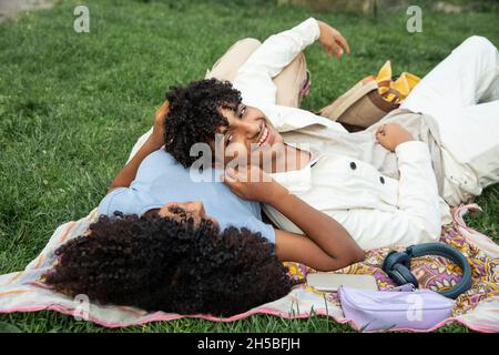 Weibliche und männliche Jugendliche reden, während sie auf Gras liegen Stockfoto