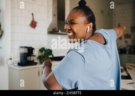 Fröhliche Frau tanzt, während sie zu Hause Musik hört Stockfoto