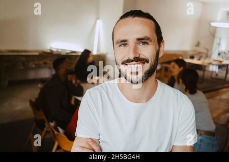 Porträt eines lächelnden männlichen Programmierers mit Kollegen im Hintergrund im Büro Stockfoto