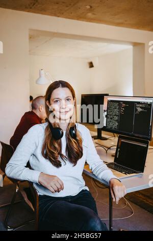 Portrait einer weiblichen Programmiererin mit Laptop und Computer am Schreibtisch im Büro Stockfoto