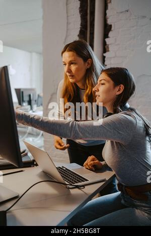 Weibliche Hacker kommunizieren, während sie im Büro am Computer arbeiten Stockfoto