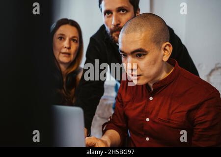 Männliche und weibliche Hacker arbeiten an einem Laptop in einem Startup-Unternehmen Stockfoto