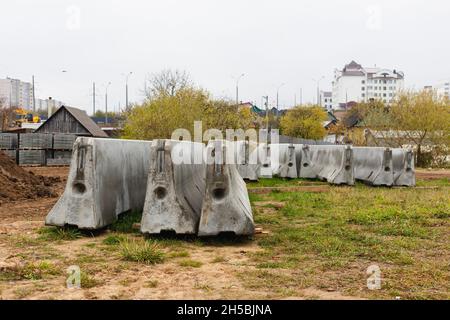 Betonstoßstangen auf einer Baustelle. Hackmaschinen für die Verkehrssicherheit. Stockfoto