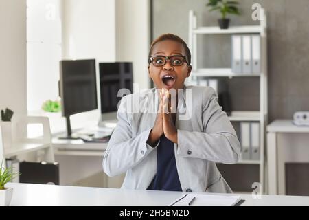 Porträt einer angenehm überraschten und glücklichen afroamerikanischen Frau, die bei der Arbeit gute Nachrichten erhielt. Stockfoto