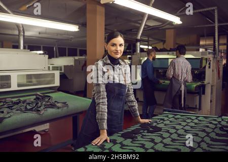 Porträt einer Schuhfabrikarbeiterin, die an einem Schreibtisch mit Mustern für zukünftige Schuhe steht. Stockfoto