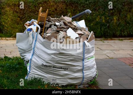 Warschau, Polen - 20. Oktober 2021: Gefüllt mit Baumüll wurde der Müllsack auf dem Bürgersteig auf den Rasen gesetzt. Diese Tasche enthält constructio Stockfoto