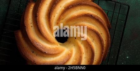 Bundt-Kuchen mit Zuckerglasur und Kokosnuss auf dunkelgrünem alten Betongrund. Selektiver Fokus. Draufsicht mit Kopierbereich. Stockfoto