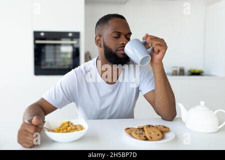 Schwarzer Mann, der an Schlaflosigkeit leidet und Kaffee trinkt Stockfoto