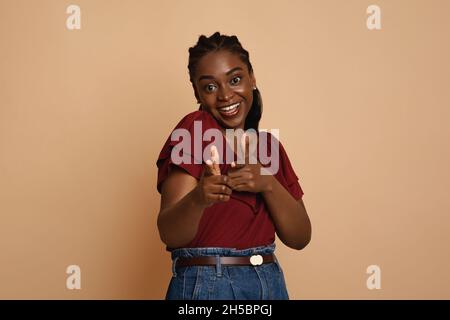 Positive afroamerikanische junge Frau, die vor der Kamera anzeigt Stockfoto