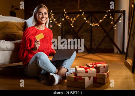 Weihnachtsgeschäfte. Lächelnde Dame mit Laptop und Kreditkarte Stockfoto