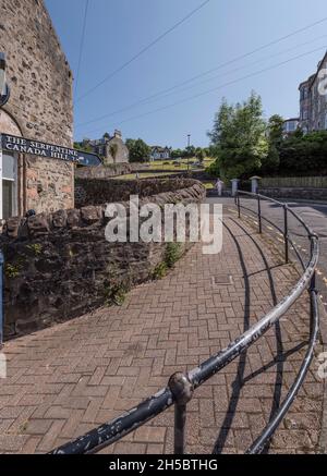 Frau, die sich in der Nähe des Serpentins kurz über der ersten von vielen Haarnadelkurven auf der steilen Straße nach Canada Hill, Rothesay, Isle of Bute, ausruhte. Stockfoto