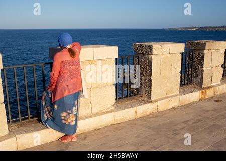 Sizilien, Siracusa, Ortigia - 20. Juli 2021: Menschen, die das Meer auf der Promenade von Ortigia betrachten Stockfoto
