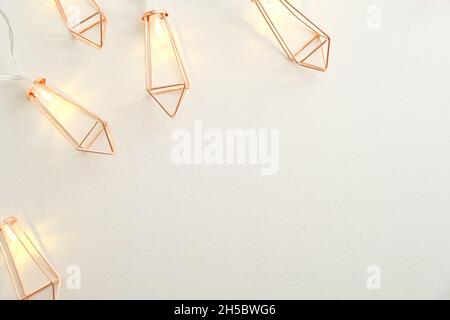 Rosa Weihnachtslichter Girlande auf weißem Tisch. Weihnachtliche Inneneinrichtung. Flach liegend, Draufsicht, Kopierbereich. Weihnachtskarten-Design. Stockfoto