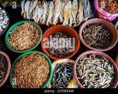 Getrockneter Fisch im Korb auf dem Markt. Der gesalzene getrocknete Fisch wird vom Verkäufer im Laden aufgehängt. Stockfoto