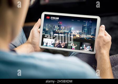 Video- und Serien-Stream-VOD-Dienst auf dem Tablet. On-Demand-fernsehsendungen oder -Filme online ansehen. Mann, der sich für Videounterhaltung von Abonnementmedien entscheidet. Stockfoto