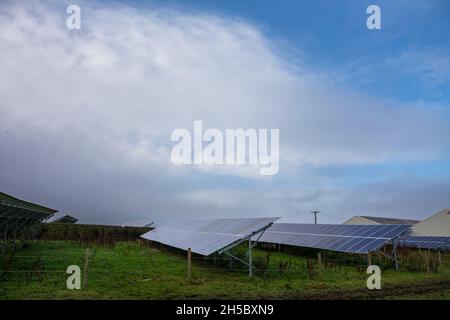 Eine Solarfarm hinter einem kleinen Gewerbepark in der Nähe von Denholme in West Yorkshire, Großbritannien, inmitten von Feldern und Ackerland auf dem Moor hinter dem Gewerbepark. Stockfoto