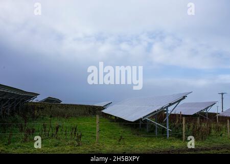 Eine Solarfarm hinter einem kleinen Gewerbepark in der Nähe von Denholme in West Yorkshire, Großbritannien, inmitten von Feldern und Ackerland auf dem Moor hinter dem Gewerbepark. Stockfoto