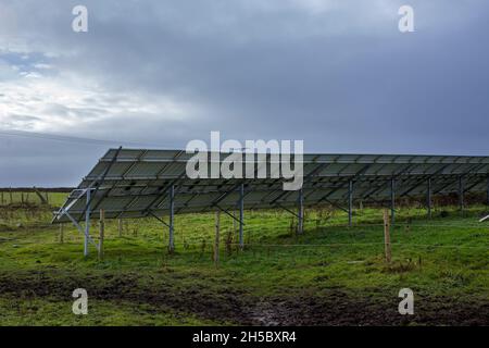 Eine Solarfarm hinter einem kleinen Gewerbepark in der Nähe von Denholme in West Yorkshire, Großbritannien, inmitten von Feldern und Ackerland auf dem Moor hinter dem Gewerbepark. Stockfoto