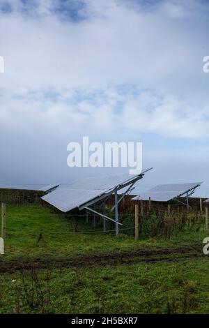 Eine Solarfarm hinter einem kleinen Gewerbepark in der Nähe von Denholme in West Yorkshire, Großbritannien, inmitten von Feldern und Ackerland auf dem Moor hinter dem Gewerbepark. Stockfoto