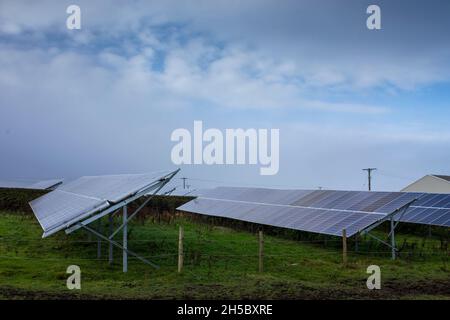 Eine Solarfarm hinter einem kleinen Gewerbepark in der Nähe von Denholme in West Yorkshire, Großbritannien, inmitten von Feldern und Ackerland auf dem Moor hinter dem Gewerbepark. Stockfoto