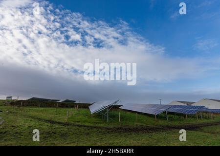 Eine Solarfarm hinter einem kleinen Gewerbepark in der Nähe von Denholme in West Yorkshire, Großbritannien, inmitten von Feldern und Ackerland auf dem Moor hinter dem Gewerbepark. Stockfoto