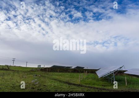 Eine Solarfarm hinter einem kleinen Gewerbepark in der Nähe von Denholme in West Yorkshire, Großbritannien, inmitten von Feldern und Ackerland auf dem Moor hinter dem Gewerbepark. Stockfoto