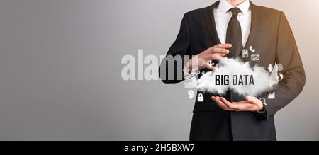 Geschäftsmann hält die Inschrift , Wort BIG DATA . Vorhängeschloss, Gehirn, Mann, Planet, Graph, Lupe, Zahnräder, Symbol für Cloud, Grid, Dokument, Brief, Telefon Stockfoto